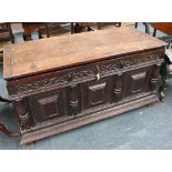 An 18th Century oak coffer, the hinged lid over a carved frieze over a paneled front with baluster