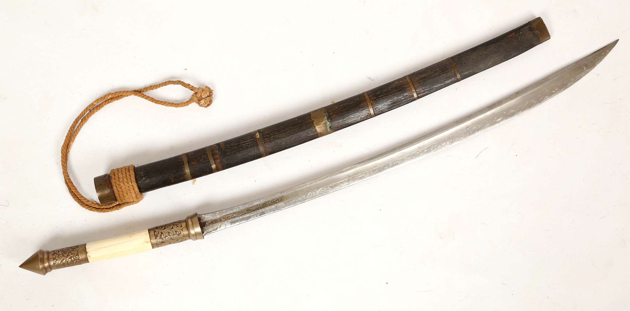 A Burmese Dha sword, brass finial with leaf decoration, bone grip, decoration to blade, 59.5cm,