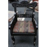 A 19th Century Anglo Indian carved ebony armchair, with squab cushions