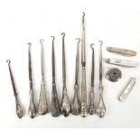 A collection of nine silver handled button hooks, three silver bladed penknives and a pill box