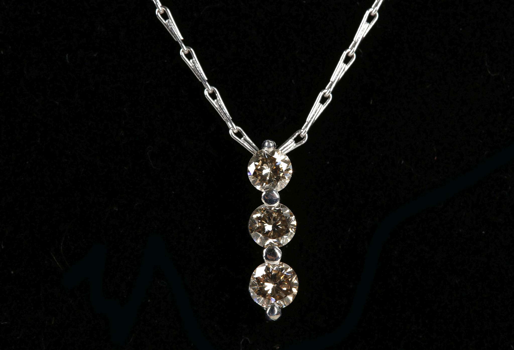 An 18ct white gold graduated 3 stone diamond pendant on an 18ct white gold chain, 0.51ct