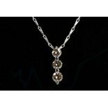 An 18ct white gold graduated 3 stone diamond pendant on an 18ct white gold chain, 0.51ct