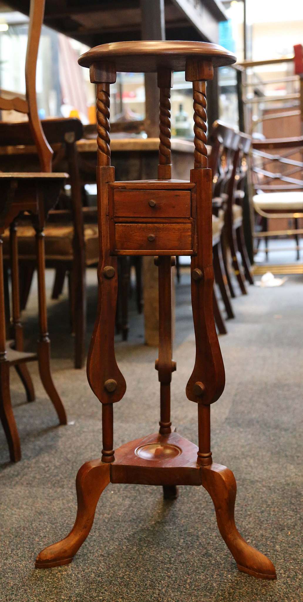 A mahogany wig stand / jardiniere, circular plinth, triangular drawers, lower gallery, 86cm high and