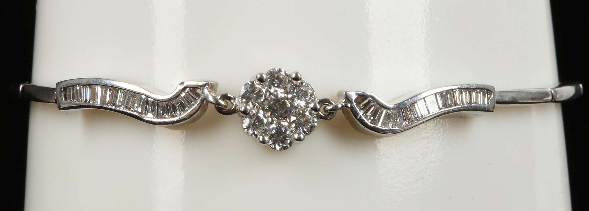 An 18ct white gold and diamond set bracelet, the central floral cluster flanked by channel set