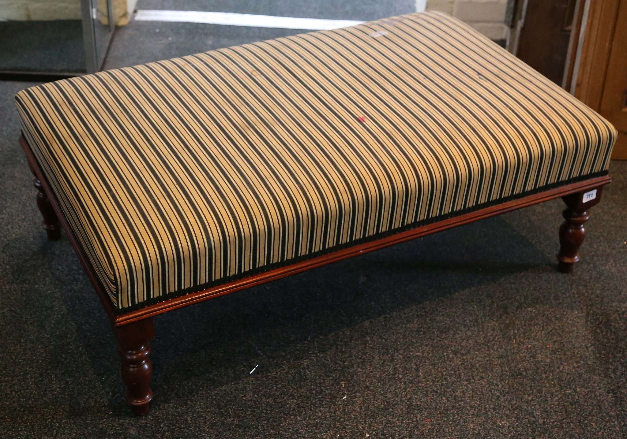 A large modern footstool, with striped upholstery,