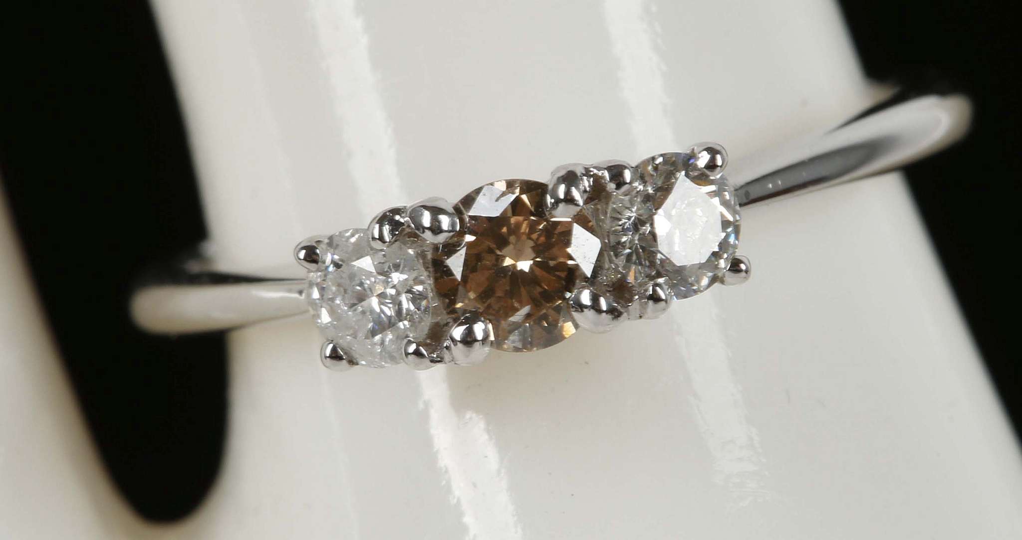 An 18ct white gold, 3 stone diamond ring, centre champagne diamond 0.24ct, with white diamond