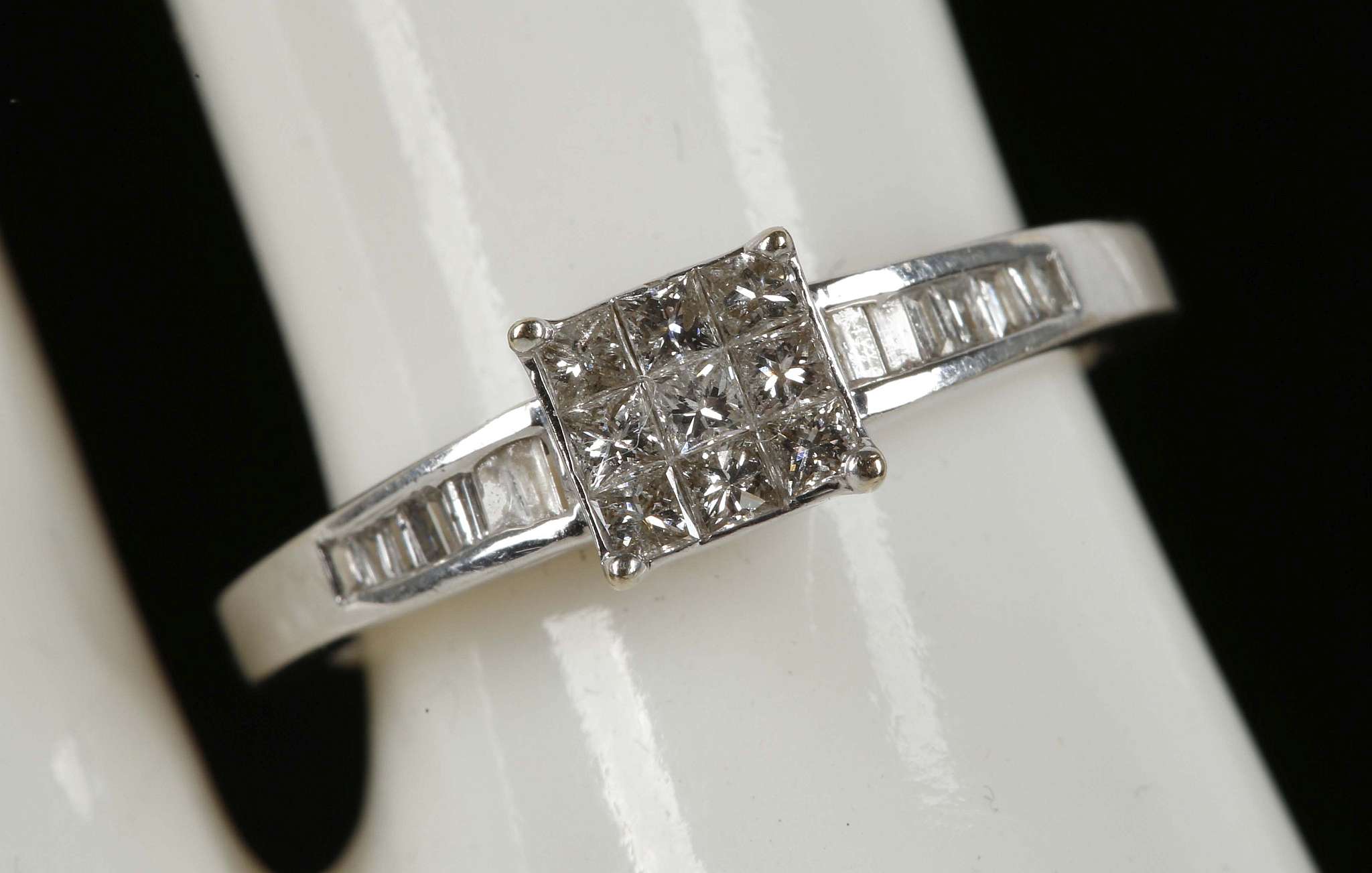 An 18ct white gold 9 stone, princess cut, diamond ring flanked by baguette diamonds to the shoulder