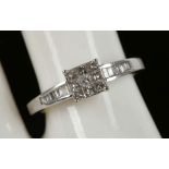 An 18ct white gold 9 stone, princess cut, diamond ring flanked by baguette diamonds to the shoulder