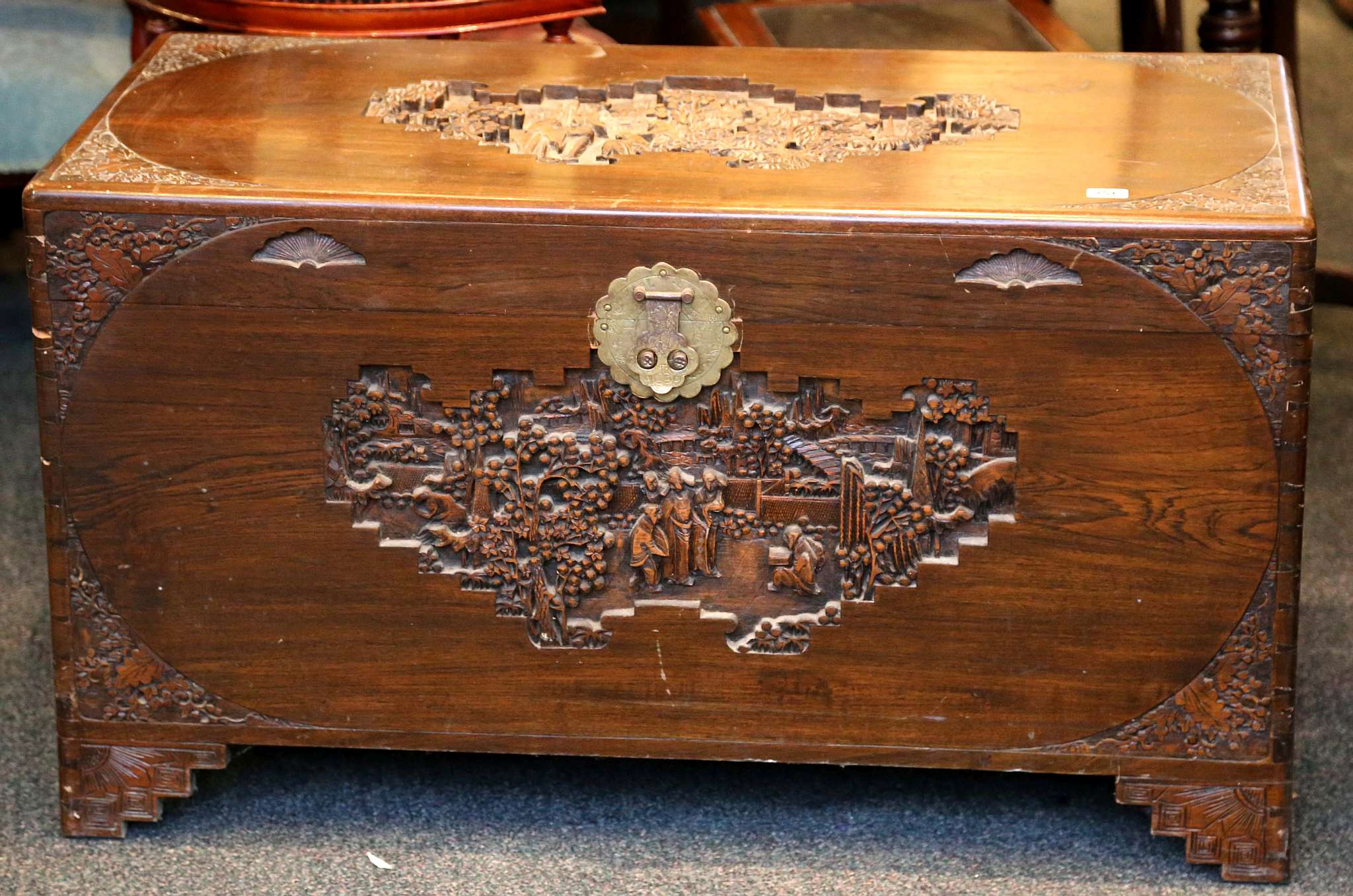 An oriental blanket box, figures and landscape carving to lid and front and floral carving to