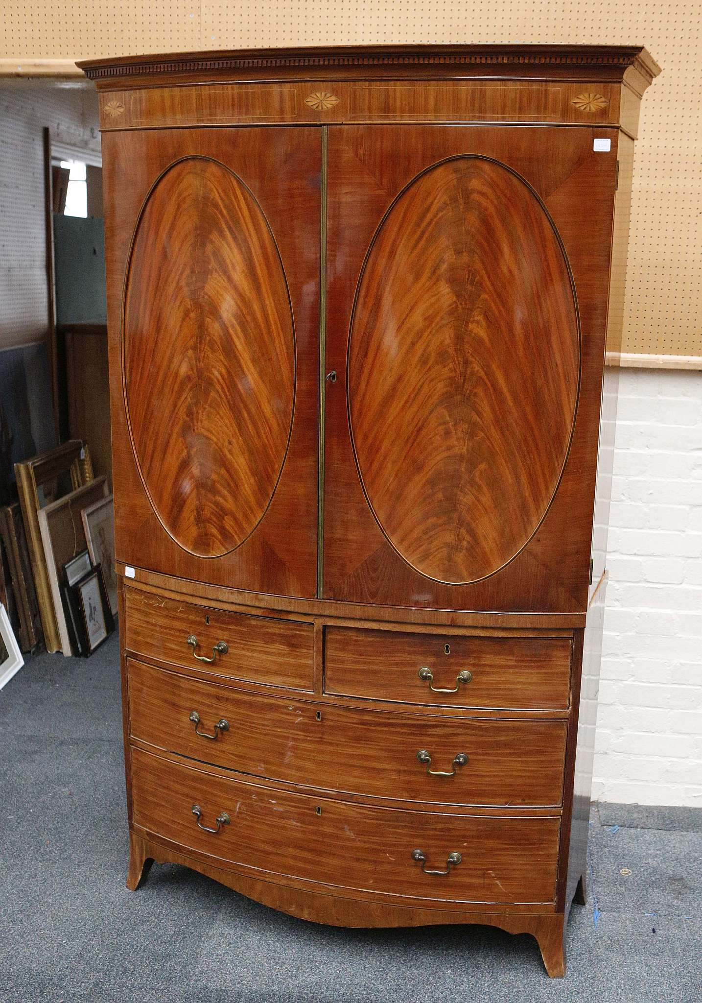 A 19th Century bow fronted flame mahogany linen press, on a chest of 2 short, 2 long drawers, raised