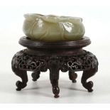 A Chinese jade washer carved with a foliate rim in the form of a lotus leaf, raised on a fitted