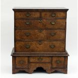 A Queen Anne walnut chest on stand, circa 1710, the chest with two short and three long drawers on a