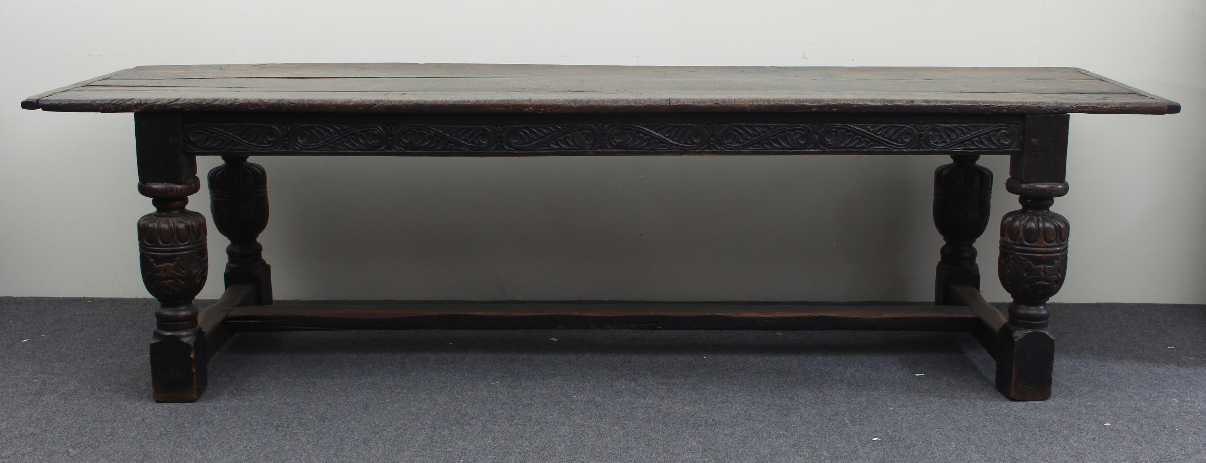 An Elizabethan style oak refectory table, the three-plank top on leaf carved rails and bulbous