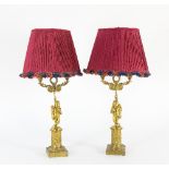 A pair of ormolu Louis XVI style two-branch lamps, supported by cherubs on a circular column, 66cm