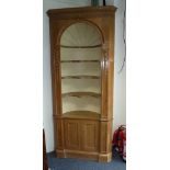 A pine corner cupboard with open shelves over, having a carved cornice and ribbed arch to the