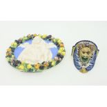 A Della Robbia type wall plaque, depicting the Virgin and Child within a wreath border, 33.5cm