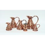 A graduated set of five copper rum jugs,