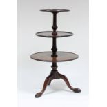 A George III mahogany three-tier dumb waiter, the dished trays on knop turned stem and tripod base,