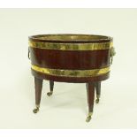 A George III mahogany and brass bound wine cooler, of oval form with lion mask ring handles,