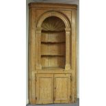 An 18th Century pine corner display cupboard of architectural form with arched fan niche supported