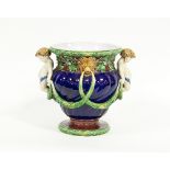 A Minton majolica jardiniere with putti in relief holding swags linked to the lion mask heads and