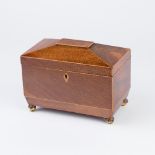 A Regency mahogany sarcophagus shaped tea caddy, on four acanthus clad ball feet,