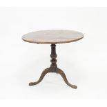 A George III oak supper table, the circular tilt-top on a baluster column and tripod base,