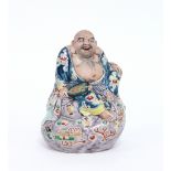 A Japanese figure of Hotei, circa 1920, seated on a cushion, decorated in bright enamels,