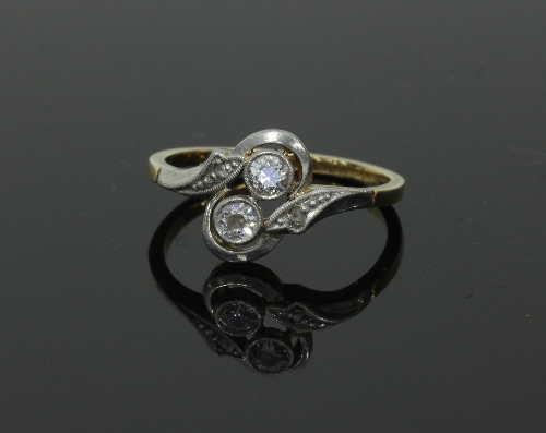 A two-stone diamond ring, in crossover type setting with a small diamond to each shoulder,