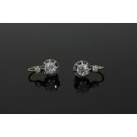 A pair of diamond earrings, each with a principal claw set diamond below a smaller diamond,