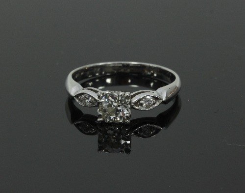 A diamond ring, the central claw set stone with a smaller diamond set in an oval to each side,