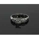 A diamond ring, the central claw set stone with a smaller diamond set in an oval to each side,