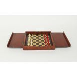 An early 19th Century travelling chess set with red stained and natural ivory pieces in a fitted