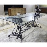 A large glass top table with a wrought iron scrolling support,