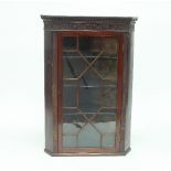 A George III mahogany hanging corner cupboard with dentil cornice above a blind fret frieze and