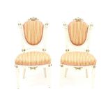 A pair of French painted salon chairs, each with shaped oval backs flanked by two reeded columns,