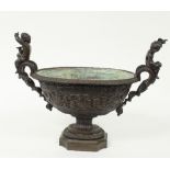 A bronze two-handled vase, of oval shape with entwined scroll handles surmounted by putti,