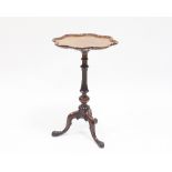 A Victorian walnut tripod table with wavy pie crust top on turned fluted baluster column and leaf