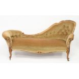 A Victorian walnut chaise longue on foliate carved cabriole scroll legs with brass castors,