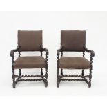 A pair of Flemish 17th Century style oak open armchairs with upholstered panel backs and seats,