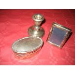 A silver pill box, a silver dwarf candlestick and a silver photograph frame (3)
