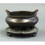 Chinese patinated bronze tripod censer, the compressed body with inverted U shaped handles at the