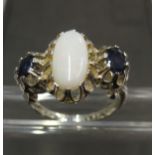 A sterling silver ring mounted with a central opal flanked by sapphires