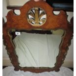 A gilt embellished walnut framed wall mirror with central fleur de lys motif