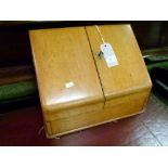 Early 20th Century light oak slope front stationary box, the double hinged cover opening to reveal a