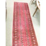 Modern Turkoman style runner, typically decorated with rosettes on a red ground within multi