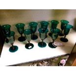 Eleven late 19th/early 20th Century green glass wines, each having a flared bowl, knopped stem and