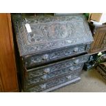 Late 19th/early 20th Century heavily carved oak bureau fitted four long drawers having carved mask