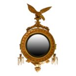 Regency gilt framed circular convex wall mirror having an elaborate eagle pediment, reeded black