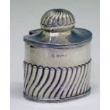 George V silver oval tea caddy having half fluted decoration, the hinged cover opening to reveal a